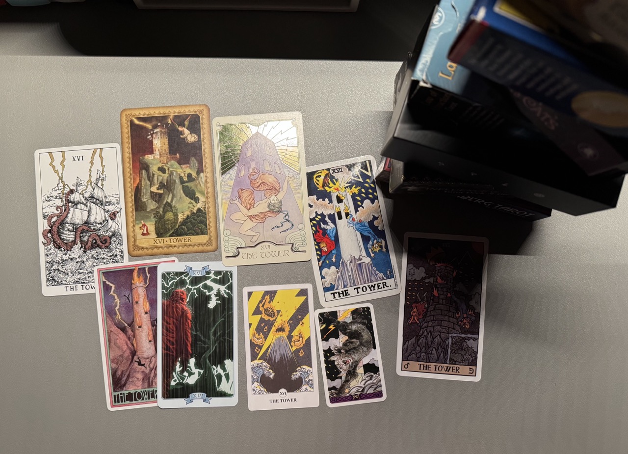 桌面上散乱地摆着九张塔罗牌,都是十六号牌「塔」,牌面上多半是崩坏的高塔、被闪电劈中的景象,还有从塔上掉下来的人;牌的旁边还摆着用牌盒叠起来的“塔”